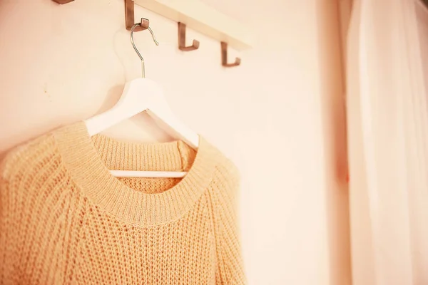 Умная зимняя одежда свитер на вешалке на белой стене backgroun — стоковое фото