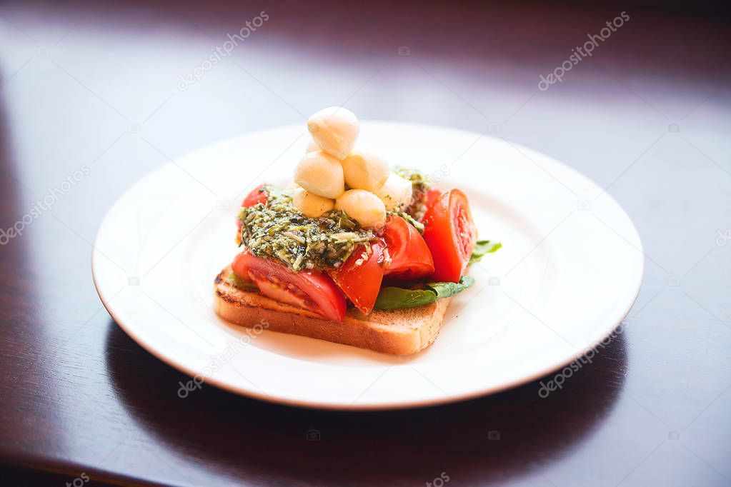 appetizer of mozzarella, toast, pesto and tomato