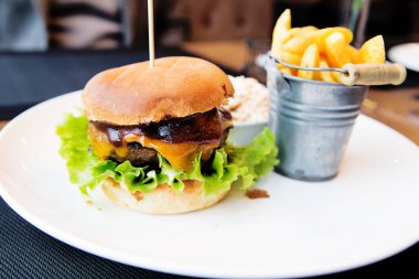 Hamburger beyaz plaka üzerinde patates kızartması ile