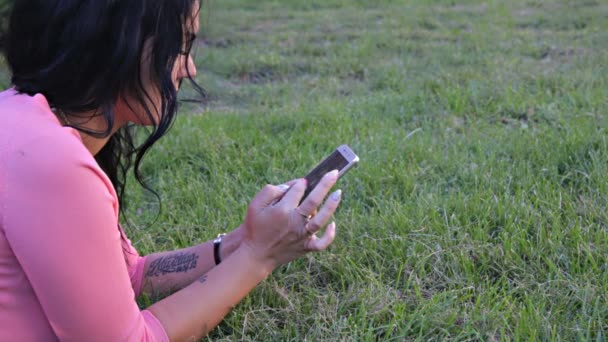 Κορίτσι στο χορτάρι με το κινητό τηλέφωνο — Αρχείο Βίντεο