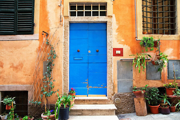 Photo of classic italian house with blue door and orange walls