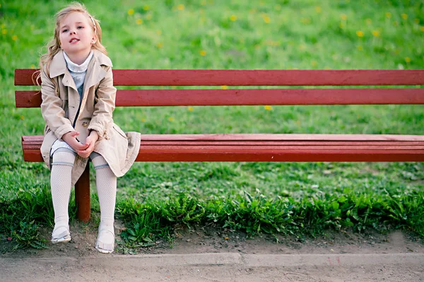 Fille dans le manteau assis sur le banc — Photo
