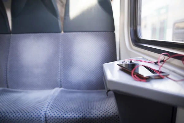 Telefone celular e fone de ouvido na mesa em um trem — Fotografia de Stock