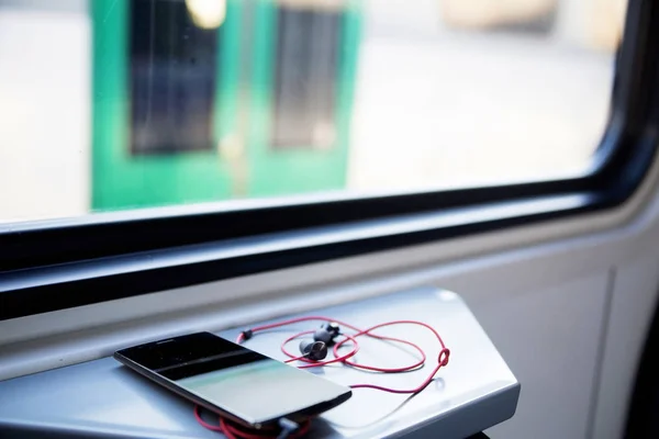 Telefone celular e fone de ouvido na mesa em um trem — Fotografia de Stock