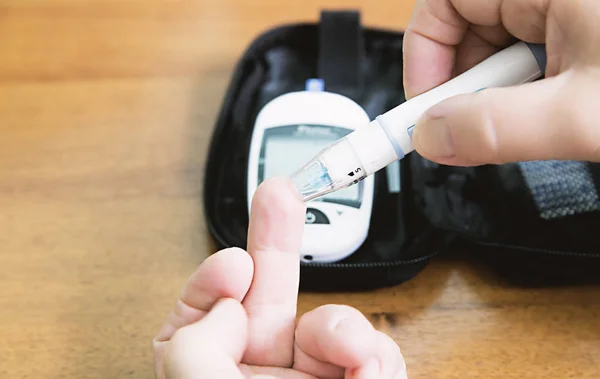 Close up van handen met behulp van lancet op vinger te controleren van hoge bloed su — Stockfoto