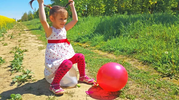 Girl bursting balloons — Stock Photo, Image