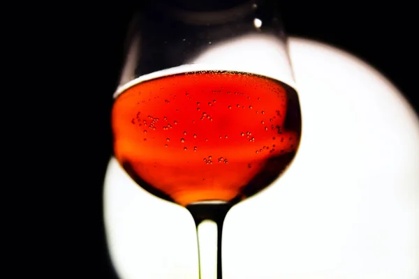 Kieliszek czerwonego wina w tyłu światła na tle czarnego & biały. — Zdjęcie stockowe