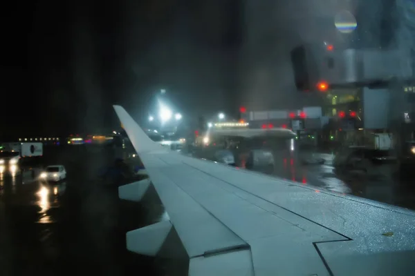 Крыло самолета через пассажирское окно на рейн вечером — стоковое фото