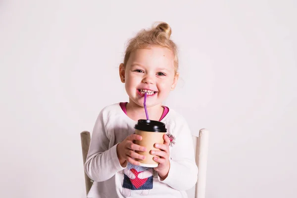 Petite fille tenant une tasse de café en papier à emporter et sourire — Photo