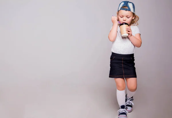 Petite fille dans un style sportif avec un verre de café à la main — Photo