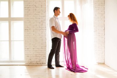 Genç bir adam güzel bir hamile kız mor elbise sarılma