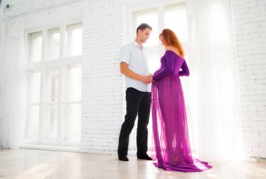 Genç bir adam güzel bir hamile kız mor elbise sarılma