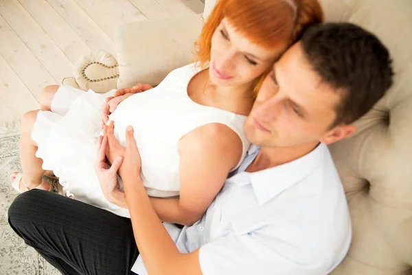 Glückliche zukünftige Eltern auf dem Sofa sitzend. Ansicht von oben — Stockfoto