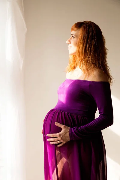 Femme enceinte en robe violette en chambre blanche — Photo