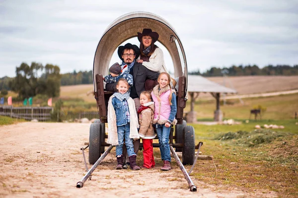 big family posing in front of camera in old American cart