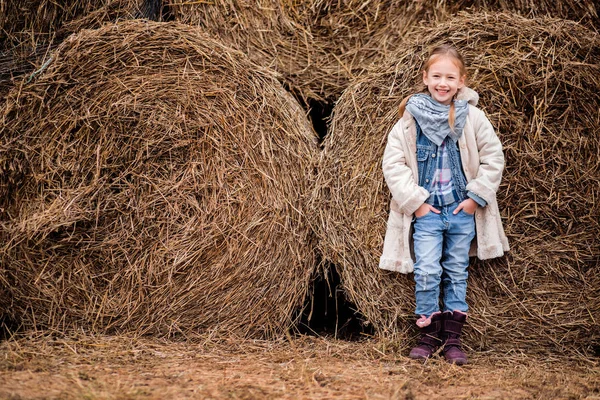 Une petite fille joyeuse à côté d'une botte de foin — Photo