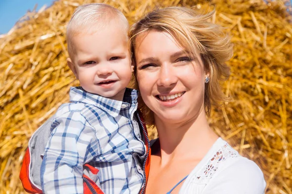 Mamma e piccolo figlio insieme sullo sfondo di un pagliaio in un — Foto Stock