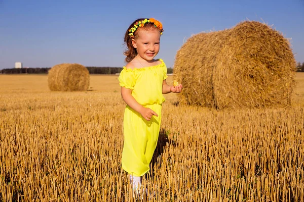 Niña en un vestido amarillo disfruta del clima —  Fotos de Stock