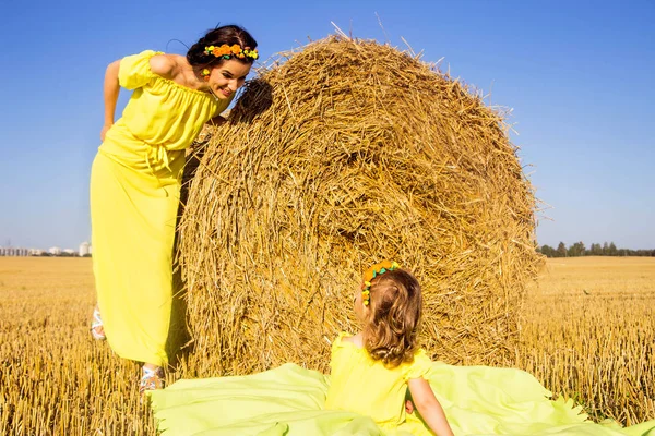 Mamá e hija en vestidos amarillos se están divirtiendo juntas —  Fotos de Stock