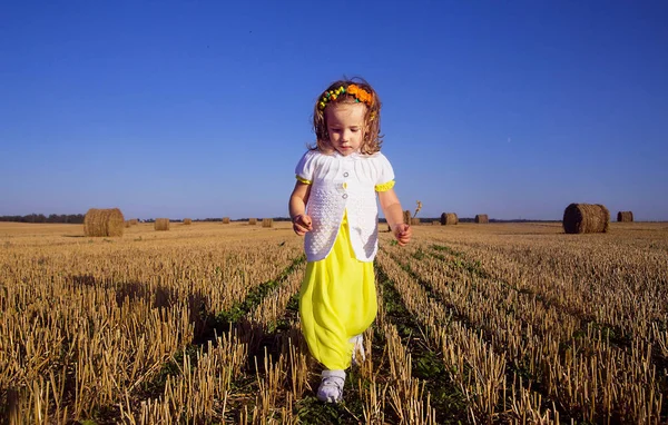 Niña en un vestido amarillo corre a través del campo —  Fotos de Stock
