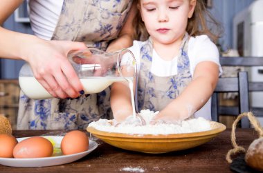 Anne ve kızı birlikte un, yumurta ve süt pişer