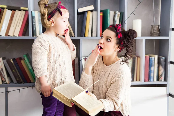 小さな女の子と彼女のお母さんがびっくりの手で本を — ストック写真