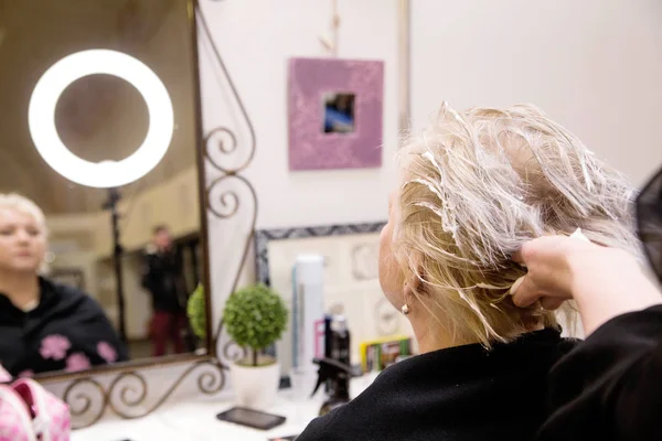 O cabeleireiro faz um penteado para uma mulher idosa — Fotografia de Stock