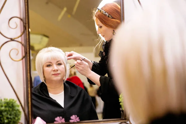 The hairdresser does a hairdo to a senior woman — Stock Photo, Image