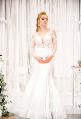 Beyaz bir arka plan karşı uzun beyaz bir elbise içinde gelin