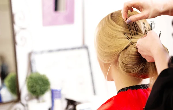 O cabeleireiro faz um penteado para uma jovem mulher — Fotografia de Stock