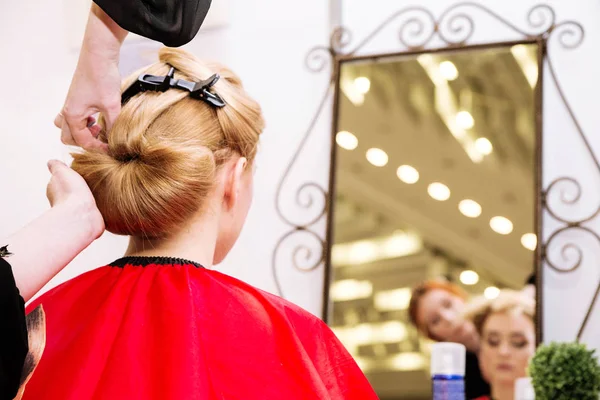 The hairdresser does a hairstyle for a young woman — Stock Photo, Image