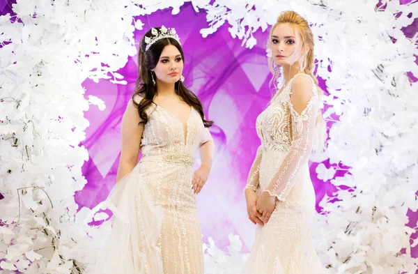 Dos modelos en la imagen de una novia en el fondo de una decoración violeta —  Fotos de Stock