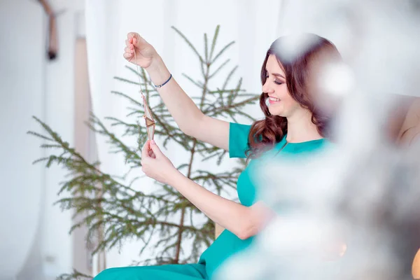 Beautiful pregnant woman in a green dress and New Year decorations — Stock Photo, Image