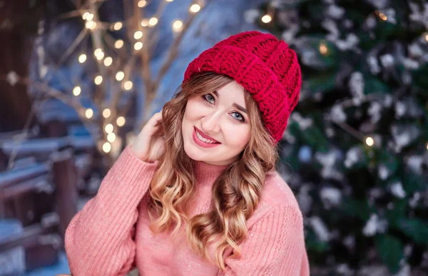 Belle fille dans un pull rose et un chapeau rouge regarde la caméra et sourit — Photo