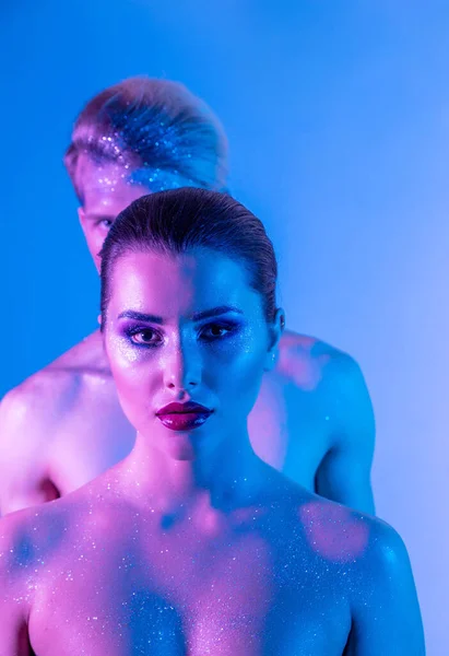 Male and female models in the studio with color filters. Close-up of models in neon purple and blue light