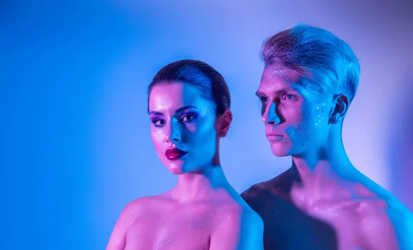 Male and female models in the studio with color filters. Close-up of models in neon purple and blue light