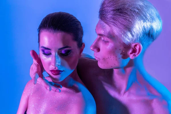 Male and female models in the studio with color filters. Close-up of models in neon purple and blue light