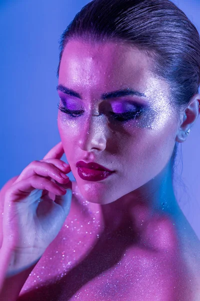 Wunderschöne brünette Modell im Studio mit Farbfiltern. Mode, Schönheit, Glühen. Nahaufnahme Gesicht einer schönen brünetten Frau in Neon helllila und blau. — Stockfoto