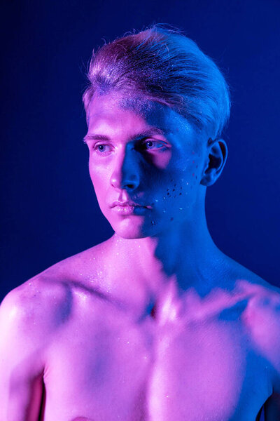 Handsome pumped up guy with naked torsos. Sports guy, attractive male body. Studio shooting with color filters