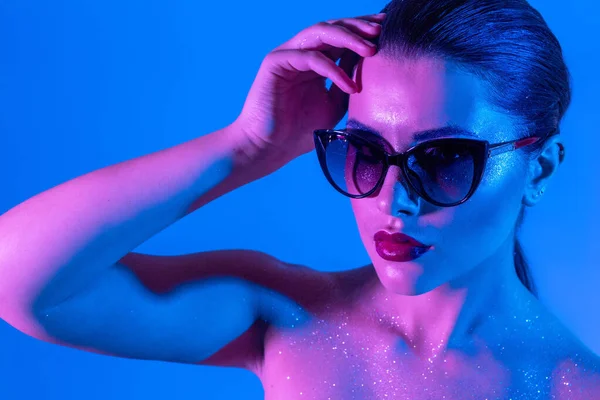 Fashionable woman in glasses iridescent background party disco style naked shoulders — Stock Photo, Image