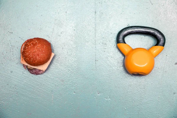 Sportkettlebell und Sandwich auf blauem Hintergrund. die Wahl zwischen Sport und Fast Food — Stockfoto