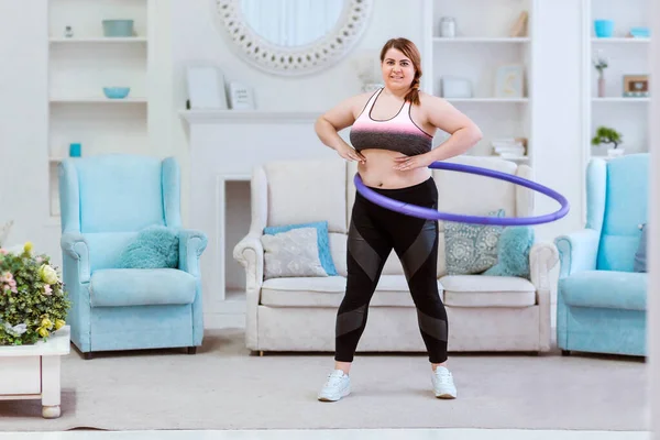Manken şişman bir kadın, evde kilo vermeye çalışıyor ve halajup ile egzersiz yapıyor. — Stok fotoğraf