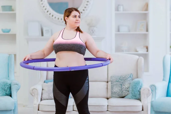 Model jest gruba kobieta, stara się schudnąć w domu i robi ćwiczenia z halajup — Zdjęcie stockowe