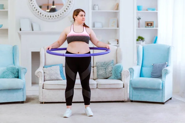 Модель толстая женщина, пытается похудеть дома и делает упражнения с halajup — стоковое фото