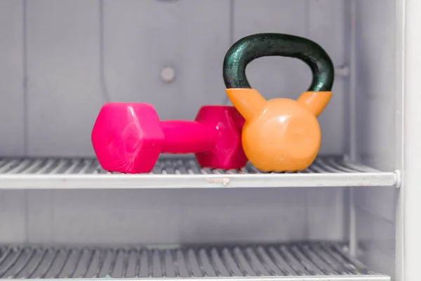 Hantel und Wasserkocher im Kühlschrankregal als Aufruf für einen gesunden Lebensstil und Sport — Stockfoto