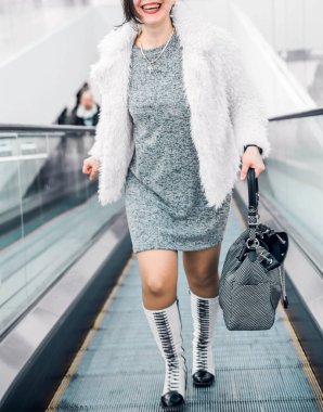 Bir kadın yürüyen merdivenden inip gülümsüyor..