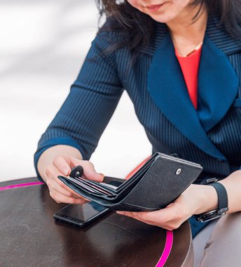 Mavi ceketli bir iş kadını elinde kredi kartı olan açık bir cüzdan tutuyor.