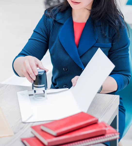 Geschäftsfrau in blauer Jacke beklebt Dokumente mit Siegel — Stockfoto