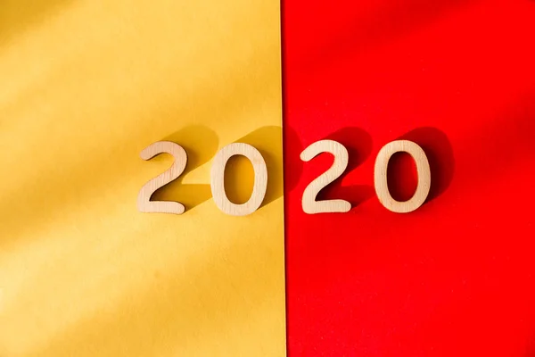 Digits 2020 on a red  and yellow background. View from above. Shadow falls on the background — Stock Photo, Image