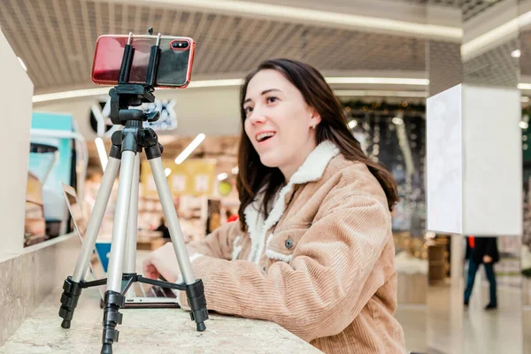 Alışveriş merkezindeki genç bir kadın blogcu dizüstü bilgisayarda çalışıyor, canlı yayınlar yapıyor, videoları kaydediyor, sosyal ağlarının takipçileriyle iletişim kuruyor.